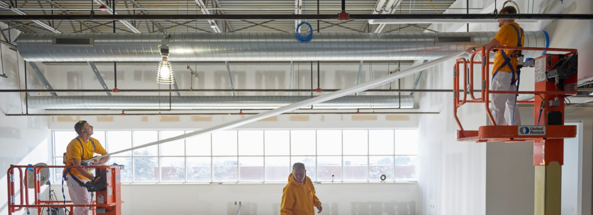 Painters on lifts coating a commercial interior