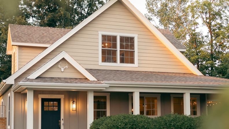 A repainted country home with a cream gable, grey siding and a navy front door