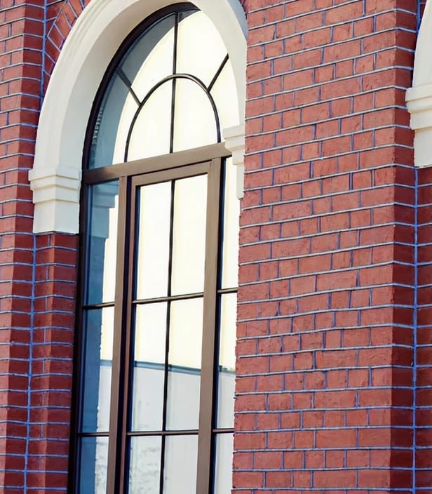 An arched window set in the red brick and mortar wall of a commercial building