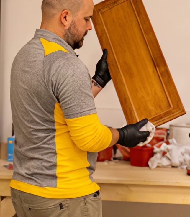 A CertaPro painter checking a refinished cabinet door in the shop